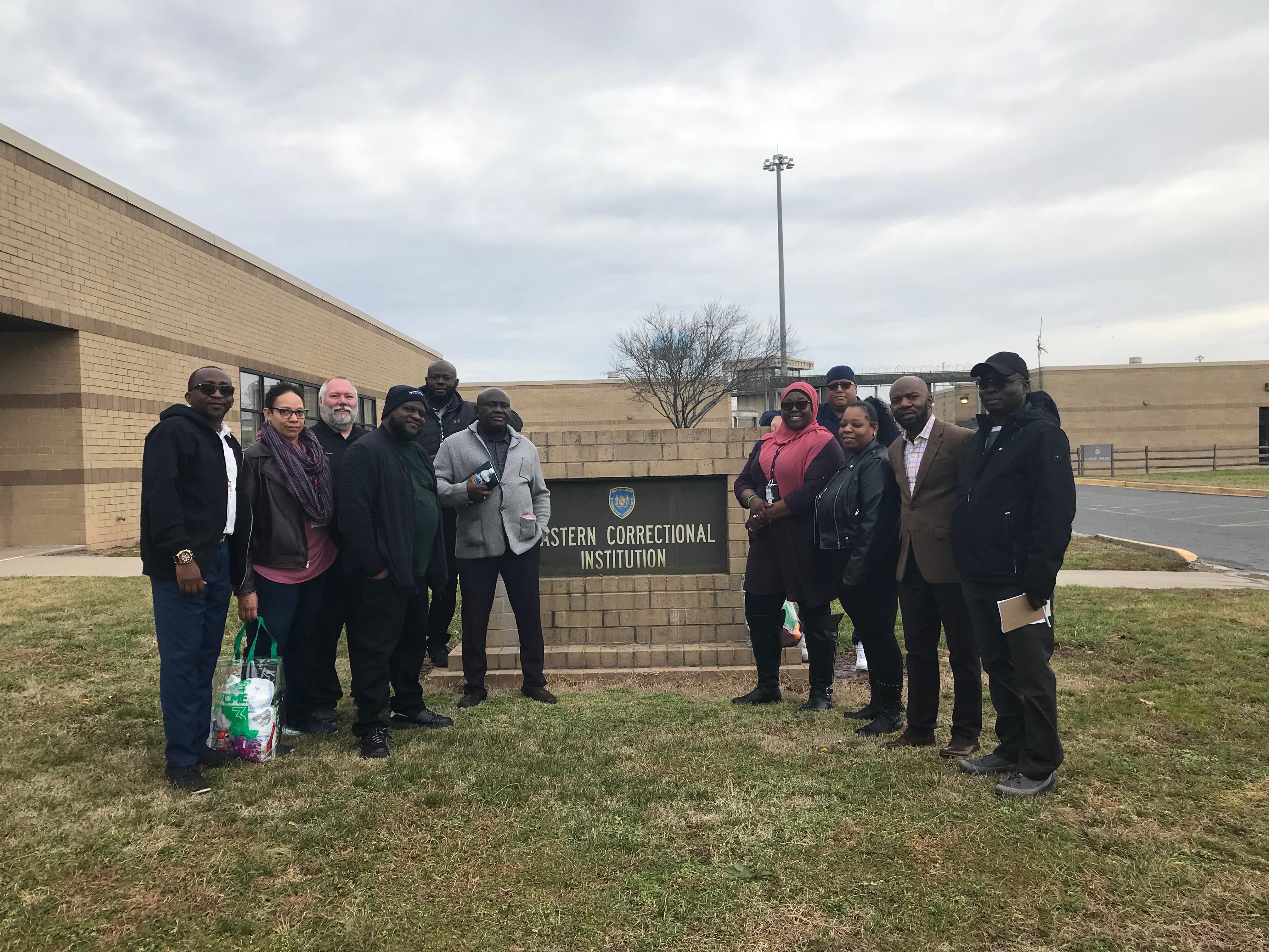 Members of the DPSCS staffing analysis team stand together in front of the Eastern Correctional Institution sign